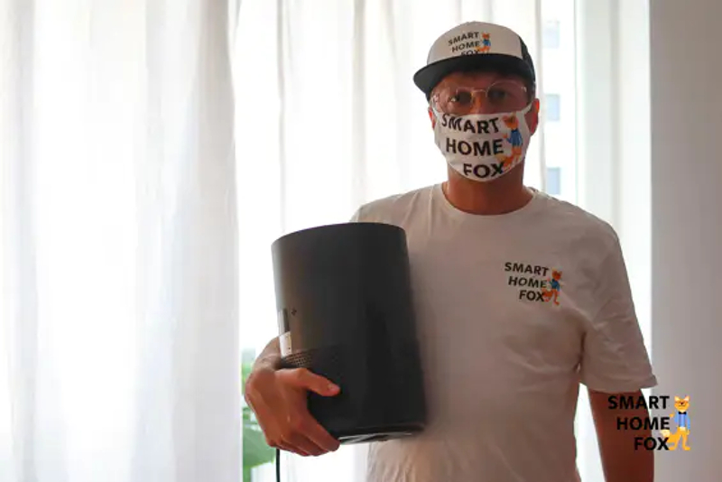 A person has an air purifier in his hand and wears a respirator mask